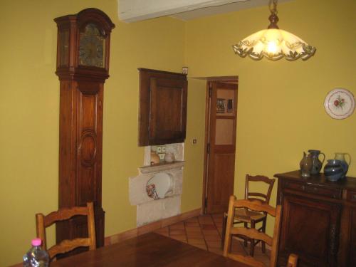 une salle à manger avec une table et une horloge grand-père dans l'établissement Les Ombelles, à Clinchamp