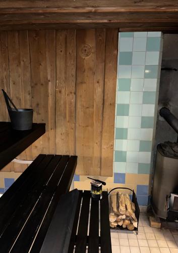 a black bench in a kitchen with a stove at Seitsemisen Torpat Log Cabin in Latovesi