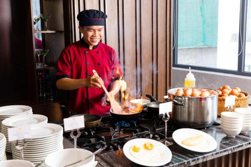 a man cooking food in a pan on a stove at Vesna Hotel Nha Trang in Nha Trang