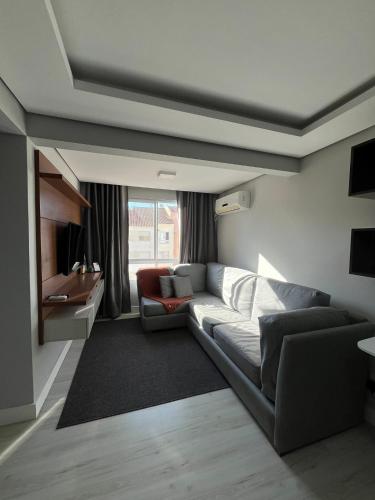 a living room with a couch and a tv at Apartamento Central 2 Quartos c Garagem in Pelotas
