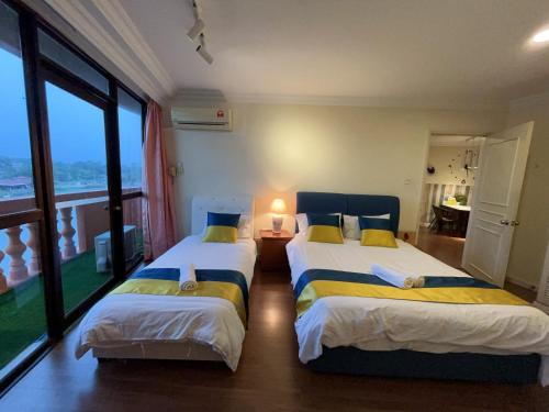two beds in a room with a large window at Riverbank suites 405 in Kuching