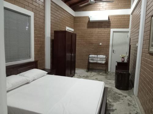 a bedroom with a white bed in a brick wall at Villa Shendel in Gampaha