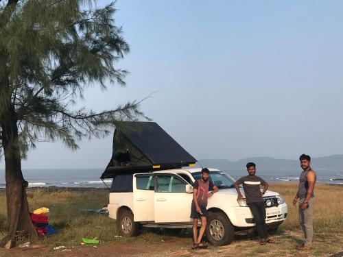 a group of three men standing next to a white car at Caravantrail-caravan Journey And Stay in Satara