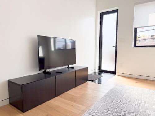 a living room with a flat screen tv on a dresser at New Ample and Cozy One Bedroom Apt in Brooklyn at Rem-Casa in Brooklyn