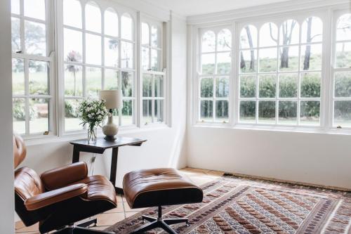 a living room with two chairs and windows at Daisy Hill Southern Highlands in Moss Vale