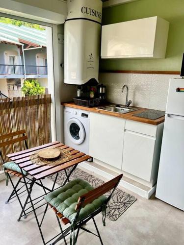 a kitchen with a table and a sink and a stove at Studio confort près des plages in Le Gosier
