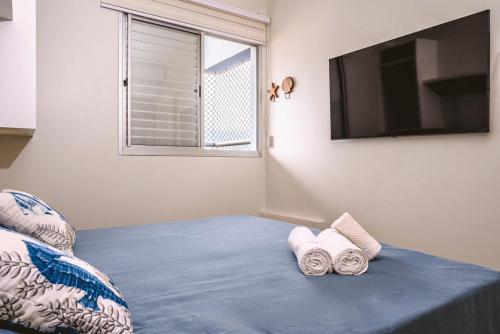 a room with a bed with a television and pillows at Helbor Atlantis by Doce Lar de Bertioga in Bertioga