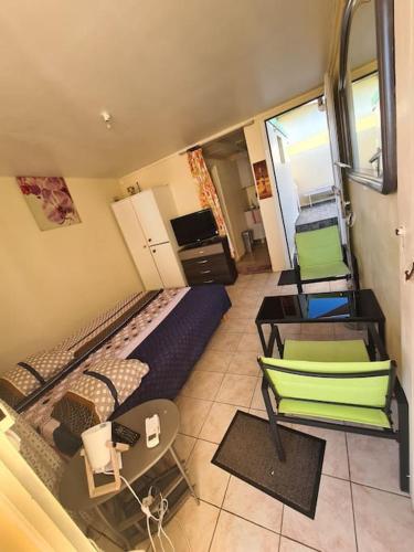 a room with a bed and two chairs and a table at Charmant studio avec terrasse in Baie-Mahault