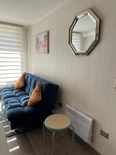 a living room with a blue couch and a mirror at Depto Nuevo Chillan Centro 2D-2B-E privado in Chillán