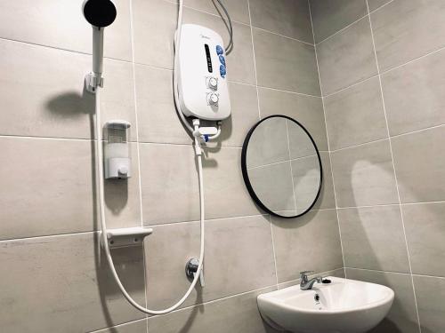 a shower in a bathroom with a sink and a mirror at Signature Mutiara Beach Resort by Glex in Melaka