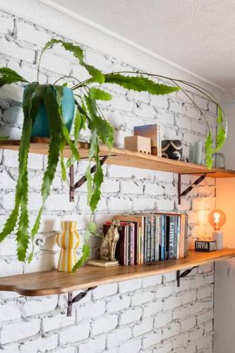 a white brick wall with wooden shelves with books at Caba Bliss - Walk to Cabarita Beach! in Cabarita Beach