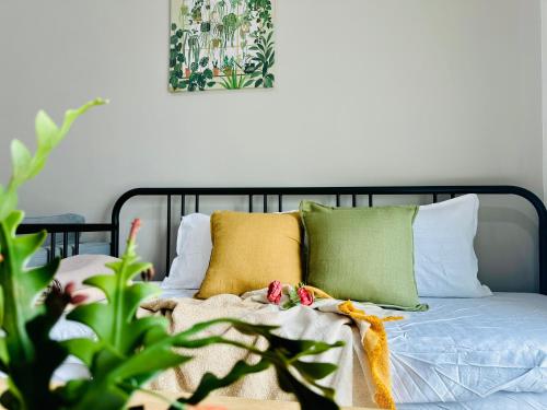 a bed with green and yellow pillows and a plant at New The Sun Homestay at Sg Nibong nearby Queensbay or PISA or FTZ Bayan Lepas HENG in Bayan Lepas