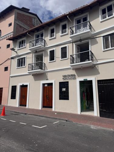 a white building with two balconies on a street at Hotel Casa Colonial Montufar in Quito