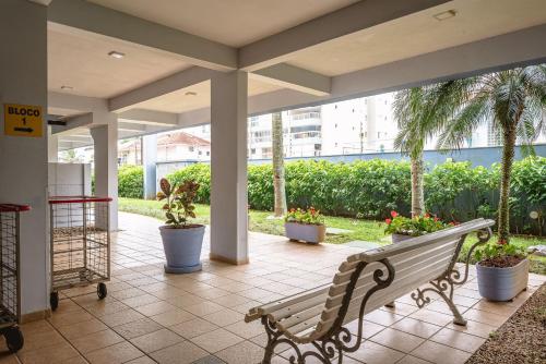 a porch with a bench and potted plants at Helbor Atlantis by Doce Lar de Bertioga in Bertioga