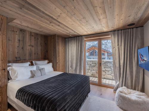 a bedroom with a bed and a large window at Chalet neuf avec piscine chauffée, espace détente, sauna, bain nordique et salle de cinéma - FR-1-570-57 in Saint-Marcel