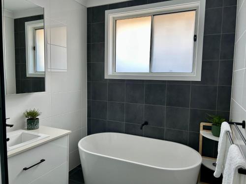 a bathroom with a white tub and a sink at Paradise in Drysdale in Dubbo