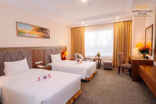 a hotel room with two beds and a desk at Muong Thanh Grand Phuong Dong in Vinh