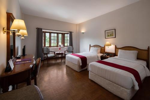a hotel room with two beds and a desk at Sinabung Hills Berastagi in Berastagi