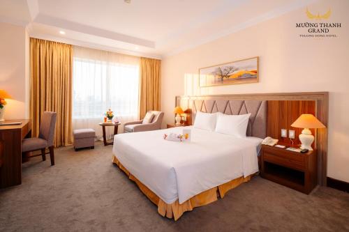 a hotel room with a large bed and a desk at Muong Thanh Grand Phuong Dong in Vinh
