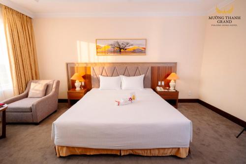 a bedroom with a large white bed and a chair at Muong Thanh Grand Phuong Dong in Vinh