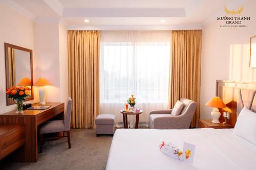 a hotel room with a bedroom with a desk and a bed at Muong Thanh Grand Phuong Dong in Vinh