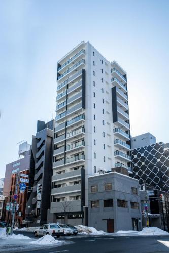 a tall white building with cars parked in front of it at MOXIE in Sapporo