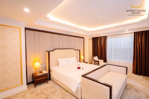 a bedroom with a large white bed and a couch at Muong Thanh Grand Phuong Dong in Vinh