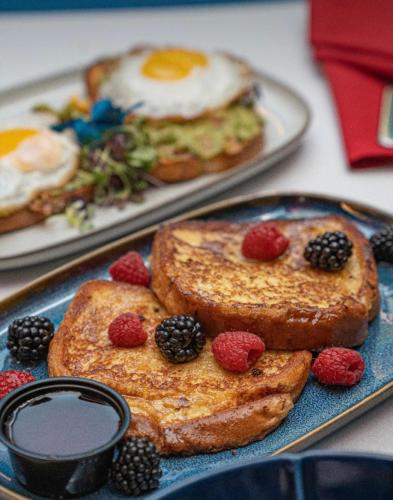 a blue plate topped with toast with fruit and eggs at IMPERIAL STAY BnB in Brooklyn