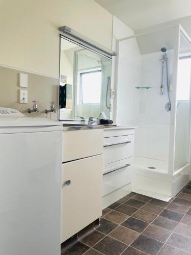 a white kitchen with a sink and a mirror at Ashleigh Court Motel-Christchurch Hagley Park in Christchurch
