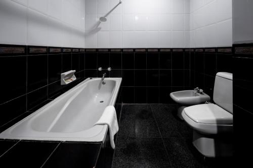 a bathroom with a tub and a toilet and a sink at Sinabung Hills Berastagi in Berastagi