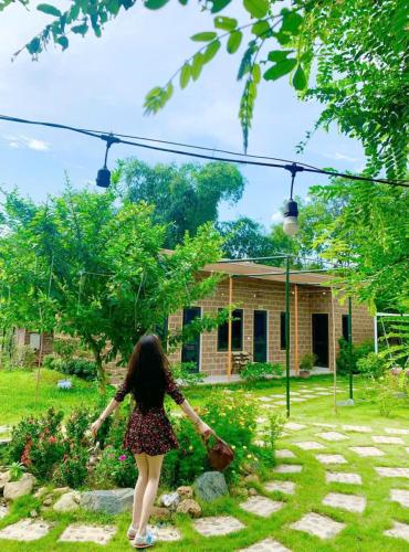 a woman walking in front of a house at Rafe Garden-Homestay Ba Vì in Ba Vì