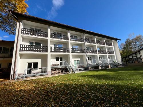 a large white building with balconies and a yard at Byt v Železné Rudě u sjezdovky s vlastním parkováním in Železná Ruda