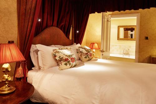a bedroom with a large white bed with pillows at Ockenden Manor Hotel & Spa in Cuckfield