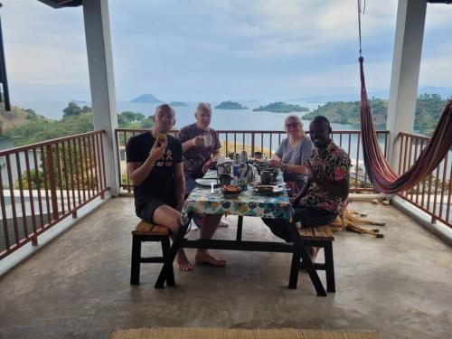a group of people sitting at a table on a balcony at Amazi Land Home and Farm Stay in Kibuye