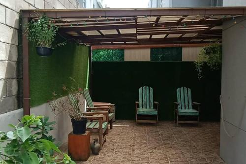 two chairs sitting on a patio with a green wall at Depto Planta Baja con Patio in Guadalajara