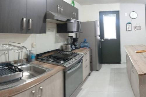 a kitchen with a sink and a stove top oven at Depto Planta Baja con Patio in Guadalajara