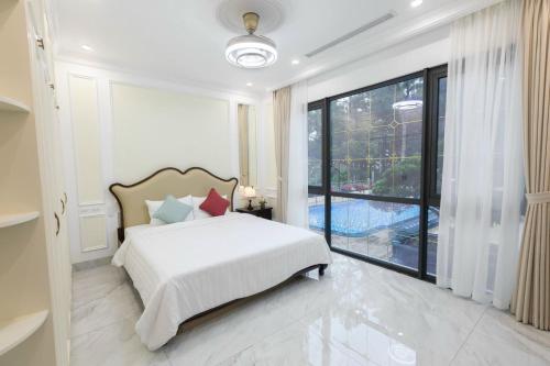 a bedroom with a bed and a large window at Flamigo Dai Lai Resort - Villa Chủ Tự Doanh in Ngọc Quang
