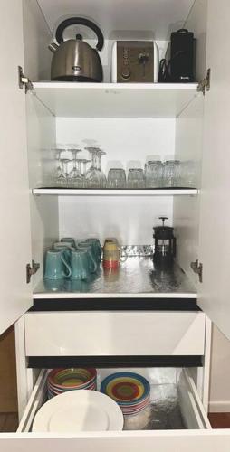 a small kitchen with a pantry with some items at Authentic Kiwi Lodge by the Lake in Rotorua