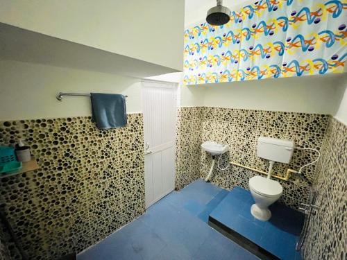 a bathroom with a toilet and a blue floor at Heritage Inn Homestay in Sibsāgar