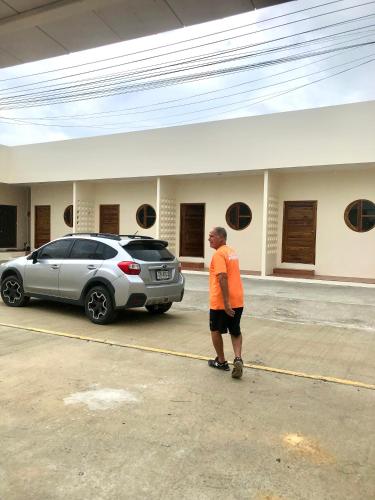 a man standing in a parking lot next to a car at บ้านศรีสุธรรม 2 Baansrisuthum 2 in Surat Thani