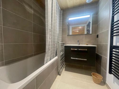 une salle de bain avec un lavabo, une baignoire et un miroir dans l'établissement Appartement moderne T4 avec jardin dans résidence neuve - FR-1-624-167, à Samoëns