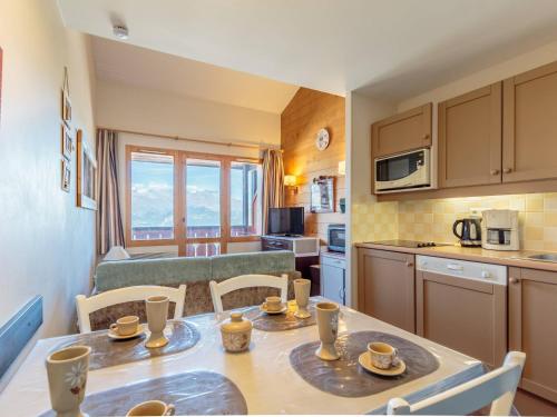 - une cuisine avec une table et des chaises avec des tasses dans l'établissement Charmant duplex 2 pièces, 4 pers., balcon, casier à skis - La Plagne - FR-1-353-146, à La Plagne Tarentaise
