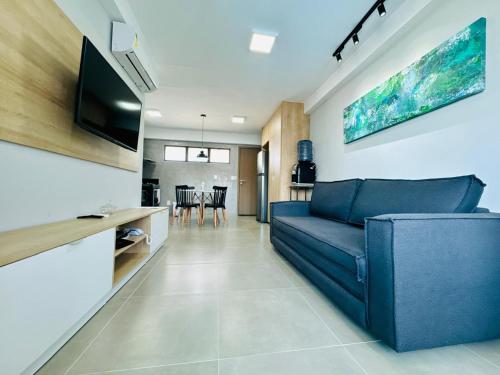 Una sala de estar con un sofá azul y una cocina. en Flat no Maui - Beira-mar - Tamandaré - Carneiros, en Tamandaré