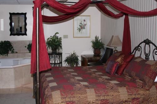 a bedroom with a bed with red curtains and a bath tub at Gladstone Inn and Suites in Jamestown