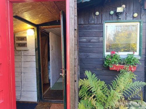 une porte rouge d'une maison avec une fenêtre et des plantes dans l'établissement Folwark Noclegowy w Nowej Morawie - Tomaszówka na wys 600 m, à Nowa Morawa