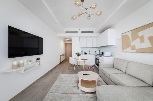 a white living room with a couch and a table at Bright 1BR with balcony in Luma 22 in Dubai