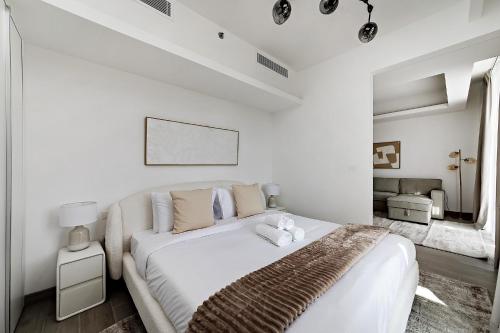 a white bedroom with a large bed with a brown blanket at Bright 1BR with balcony in Luma 22 in Dubai