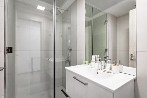 a white bathroom with a sink and a shower at Bright 1BR with balcony in Luma 22 in Dubai