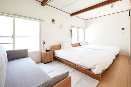 a bedroom with two beds and a couch at 2Rooms Haneda in Tokyo