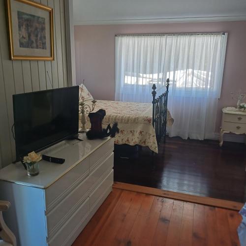 a bedroom with a dresser with a tv and a bed at Homestead BnB in Maudsland